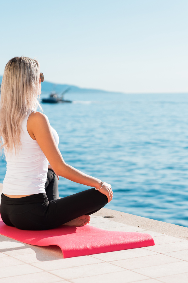 Девушка медитирует на берегу моря 