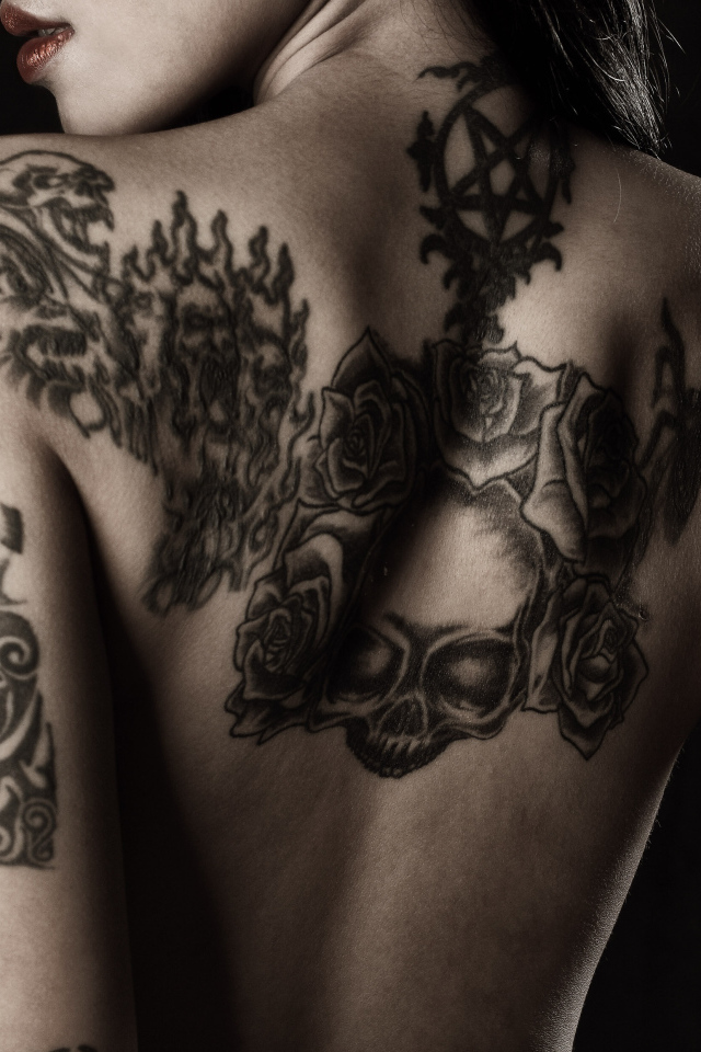 Девушка с татуировками на руках и спине