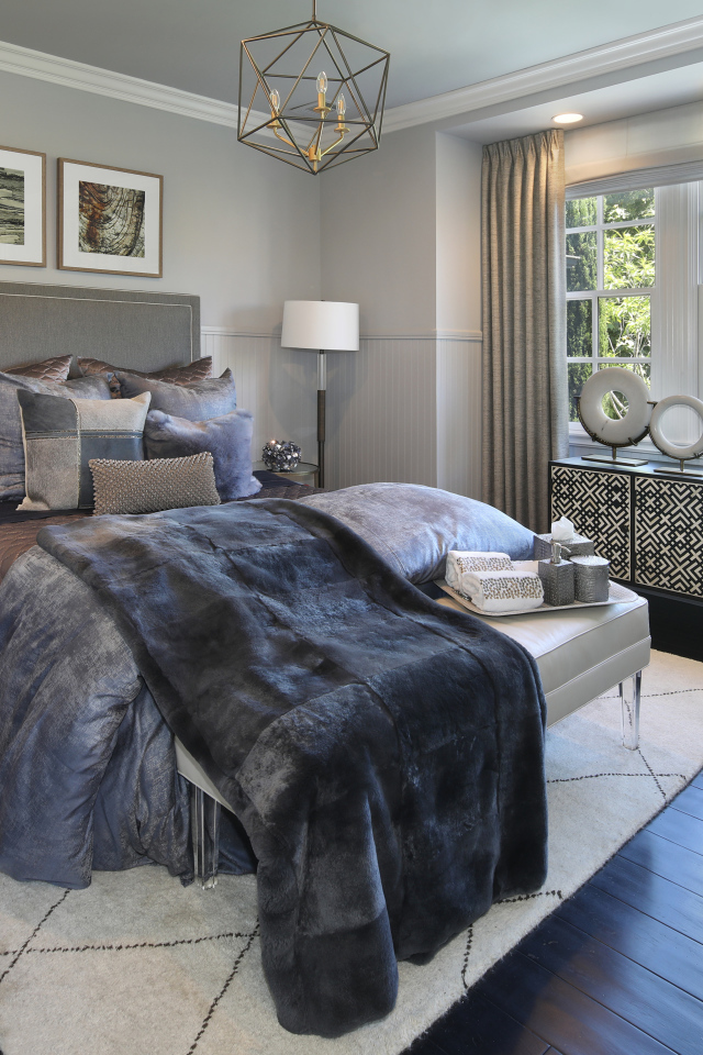 Большая кровать с мягким серым покрывалом в спальне 