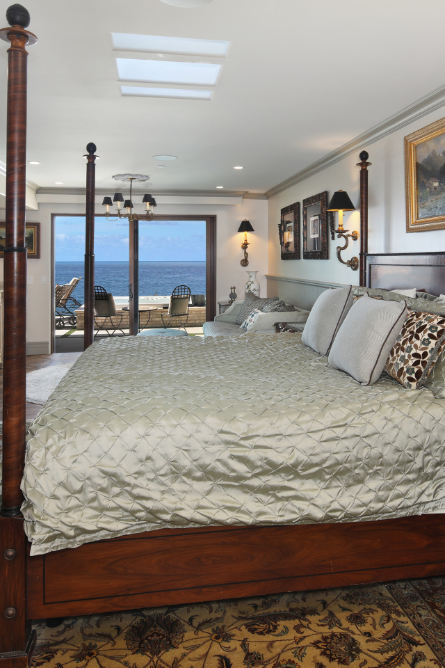 Большая деревянная кровать в спальне с видом на море 