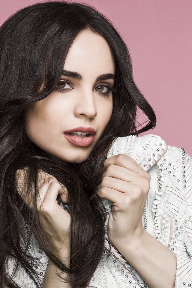 Long-haired actress Sofia Carson on a pink background