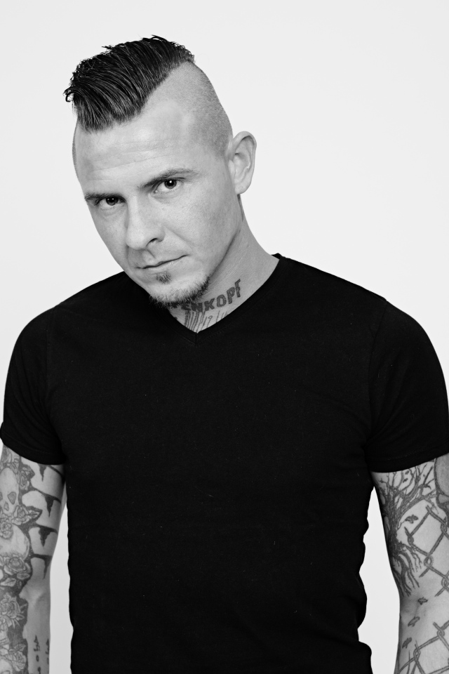 Мужчина в черной футболке с татуировками на теле