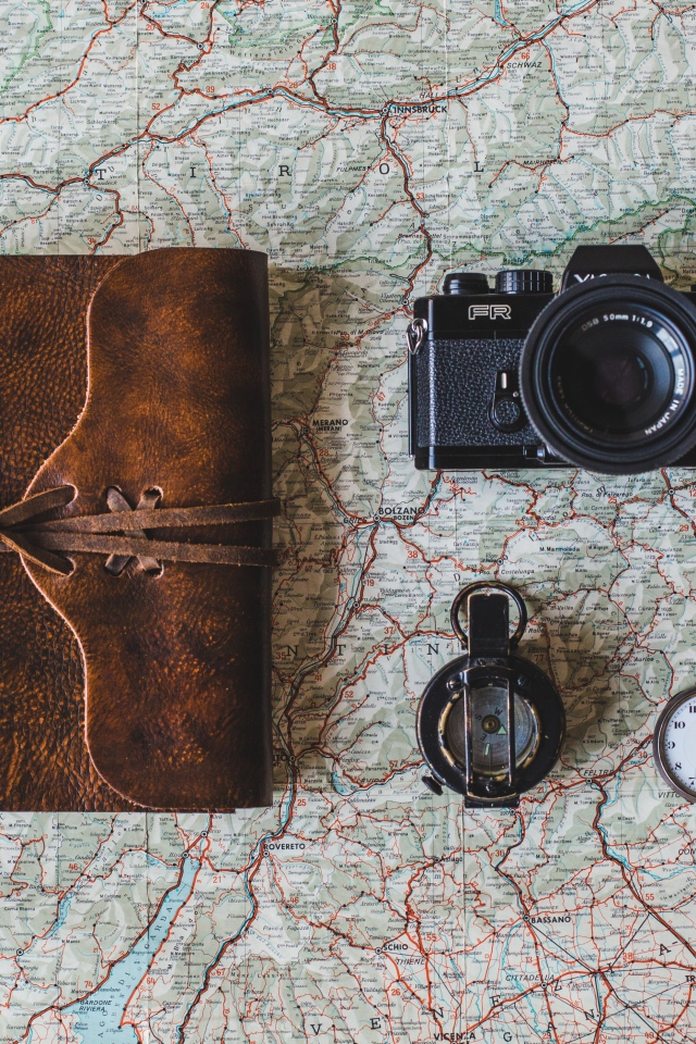 Старый фотоаппарат, компас, часы, блокнот и карта на столе