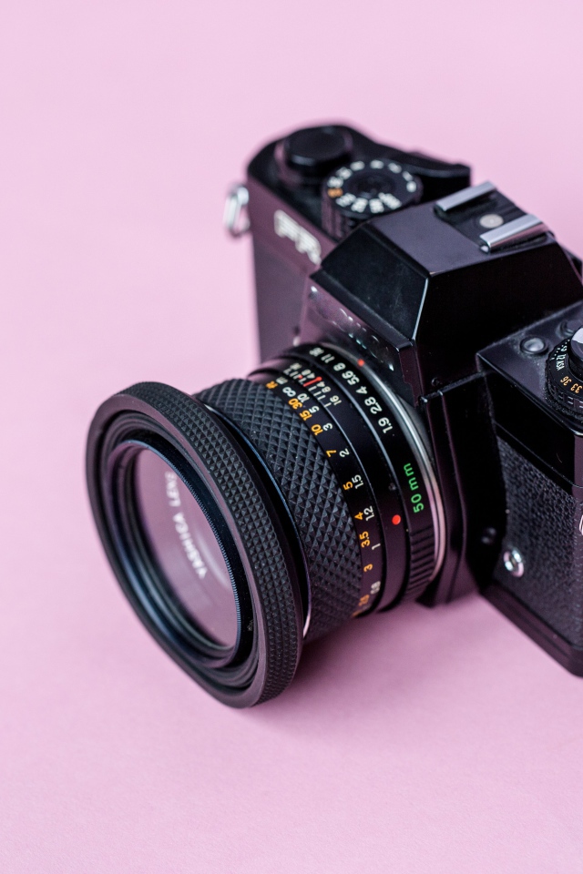 Старый фотоаппарат на розовом фоне