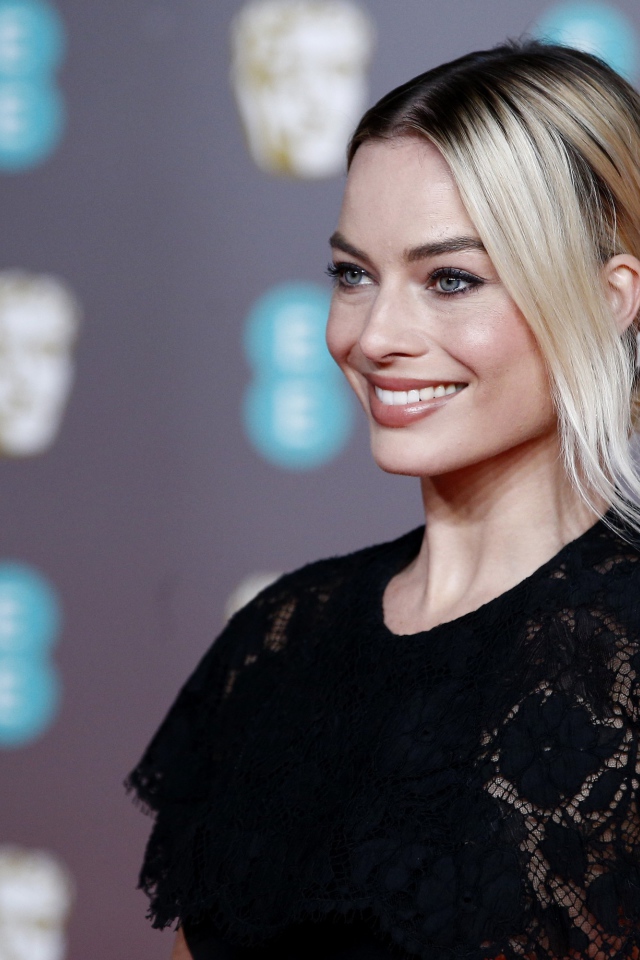 Улыбающаяся актриса Марго Робби в черном платье 