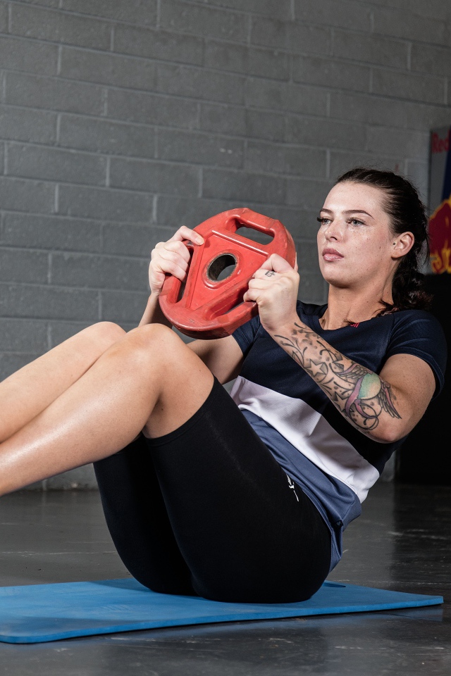 Сильная девушка с татуировками на руке качает пресс 