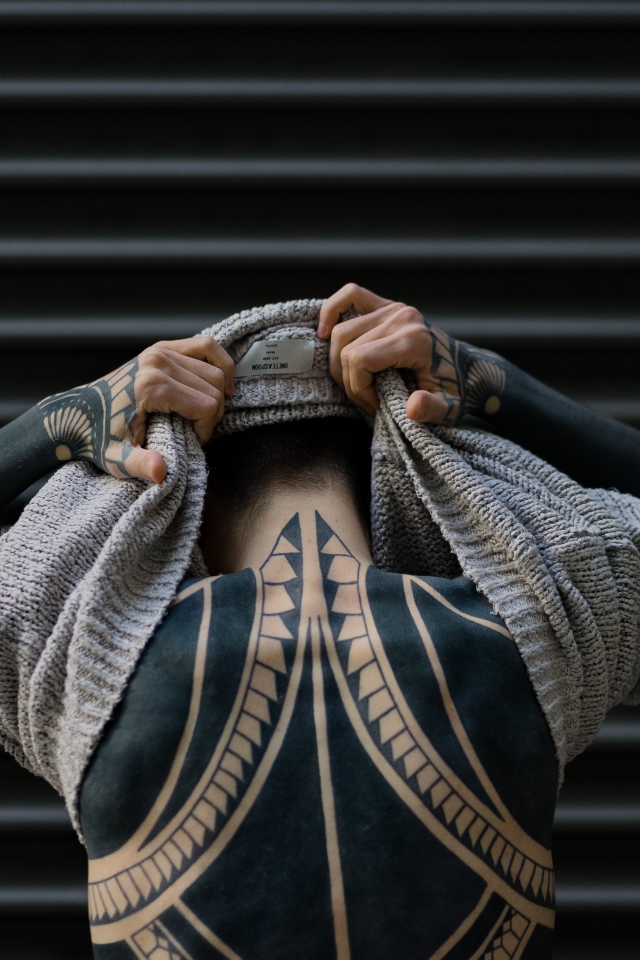 Татуировки на теле мужчины в свитере