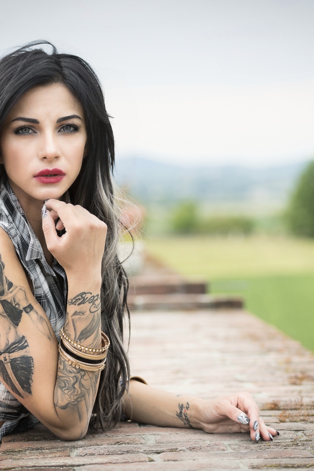 Молодая девушка брюнетка с татуировками на руках