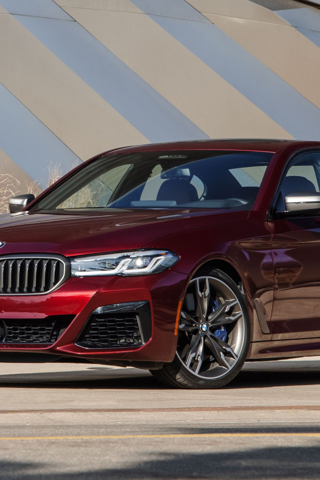 Бордовый седан BMW M550i XDrive, 2021 года у здания
