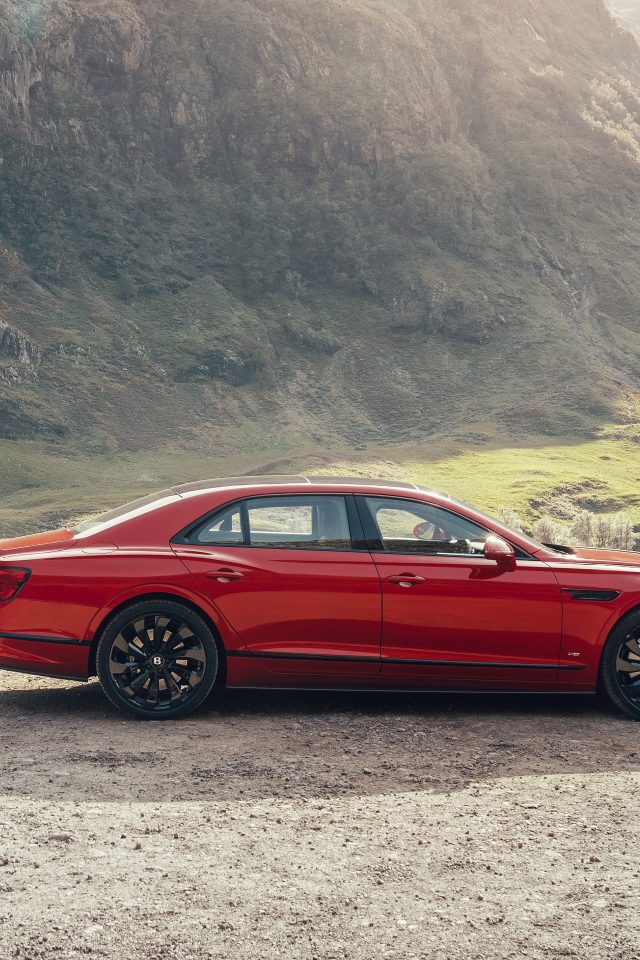 Красный автомобиль Bentley Flying Spur V8 2020 года у горы 