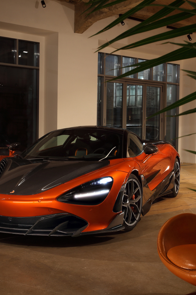 Оранжевый автомобиль  McLaren 720S у дома с креслом
