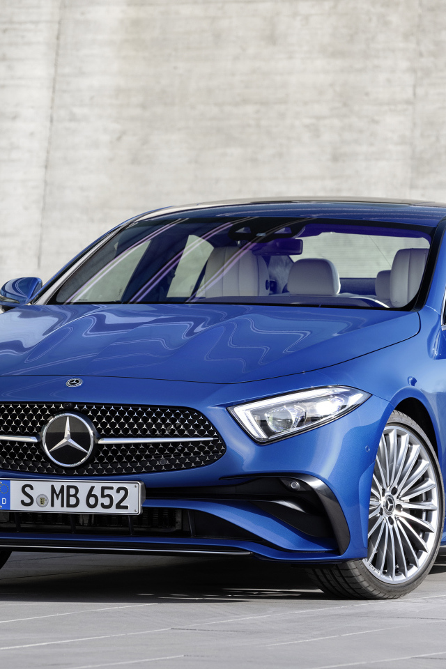 Синий автомобиль Mercedes-Benz CLS 350 AMG Line 2021 года на фоне серой стены
