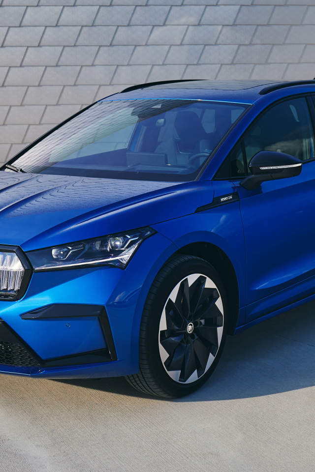 Синий автомобиль Skoda Enyaq Sportline IV 2021 года у стены