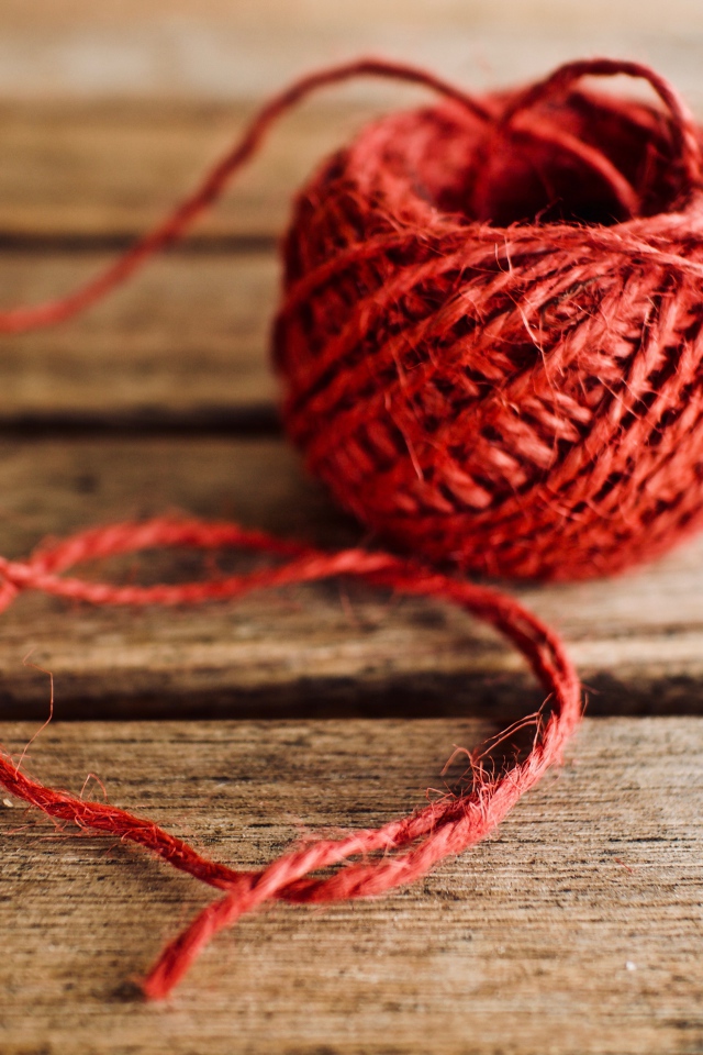 Клубок красной пряжи на деревянном столе 