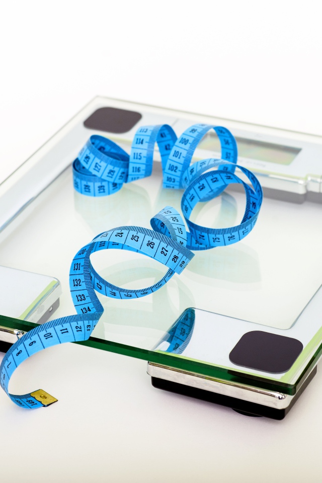 Напольные весы и сантиметр на белом фоне 