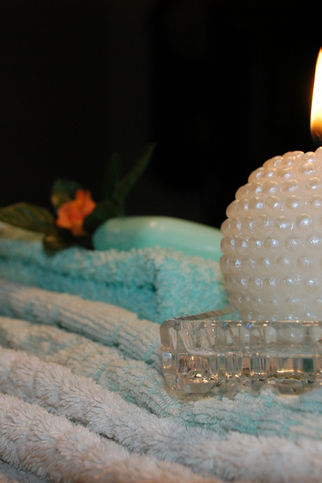 Красивая зажженная свеча с полотенцами