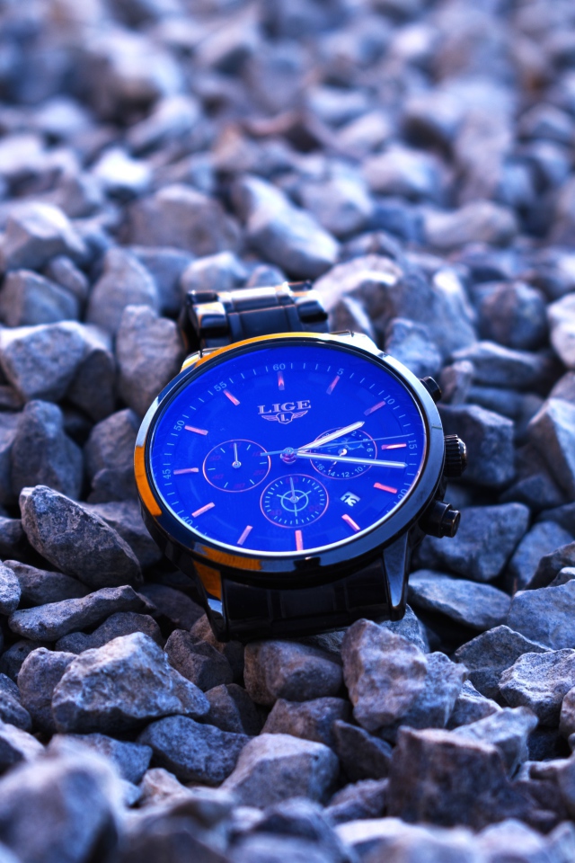 Голубые наручные часы лежат на камнях