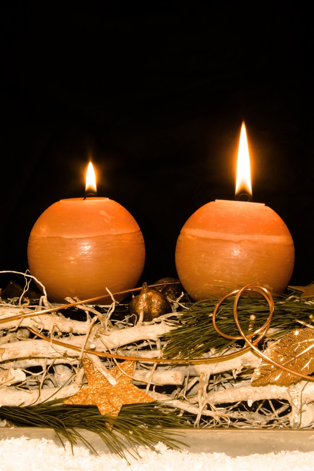 Четыре круглые зажженные свечи на черном фоне