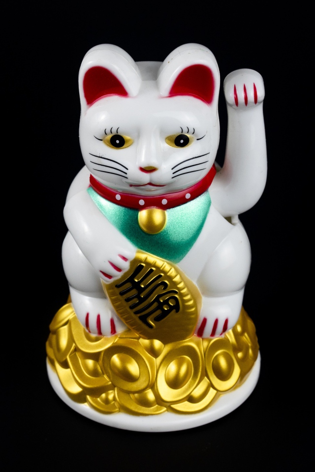 Японская фигурка манэки-нэко кошка на черном фоне
