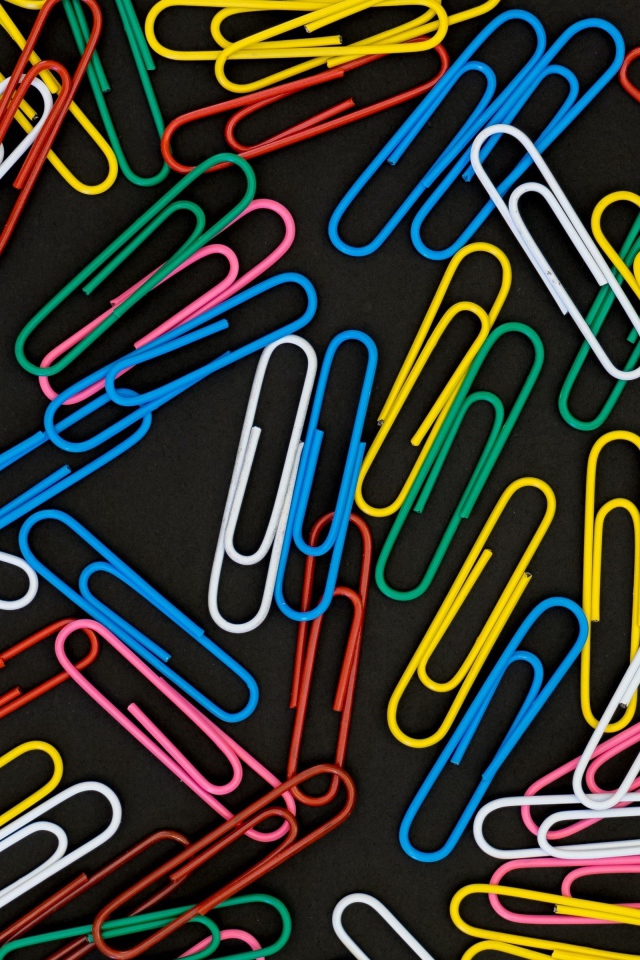 Много разноцветных скрепок на черном фоне