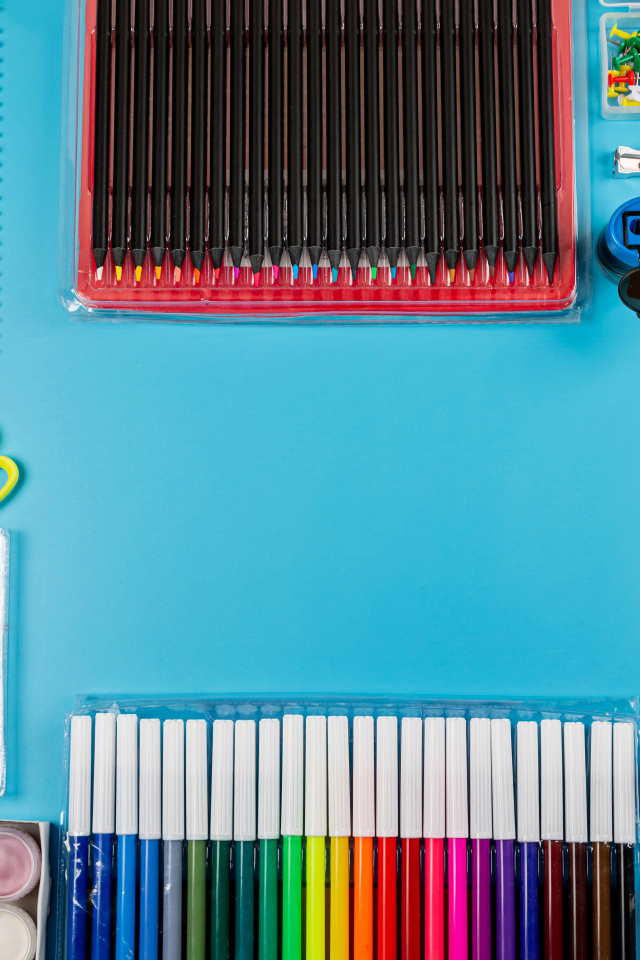 Много разноцветных канцелярских предметов на голубом фоне 