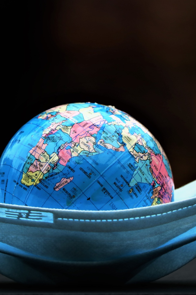 Медицинская маска и глобус на черном фоне