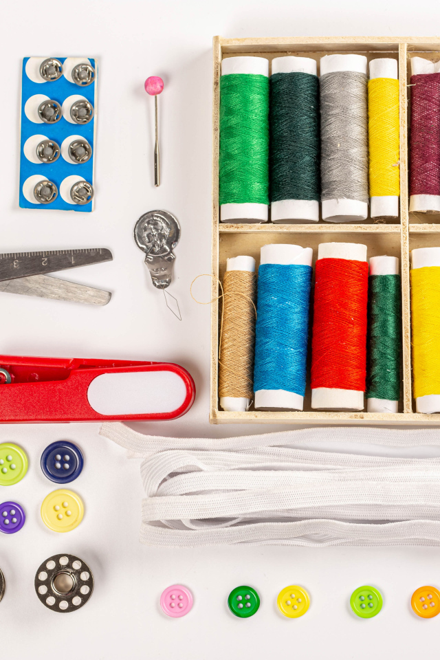 Разноцветые нитки и предметы для шитья на белом фоне 