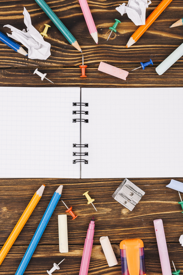 Открытый блокнот с ручками  на столе 