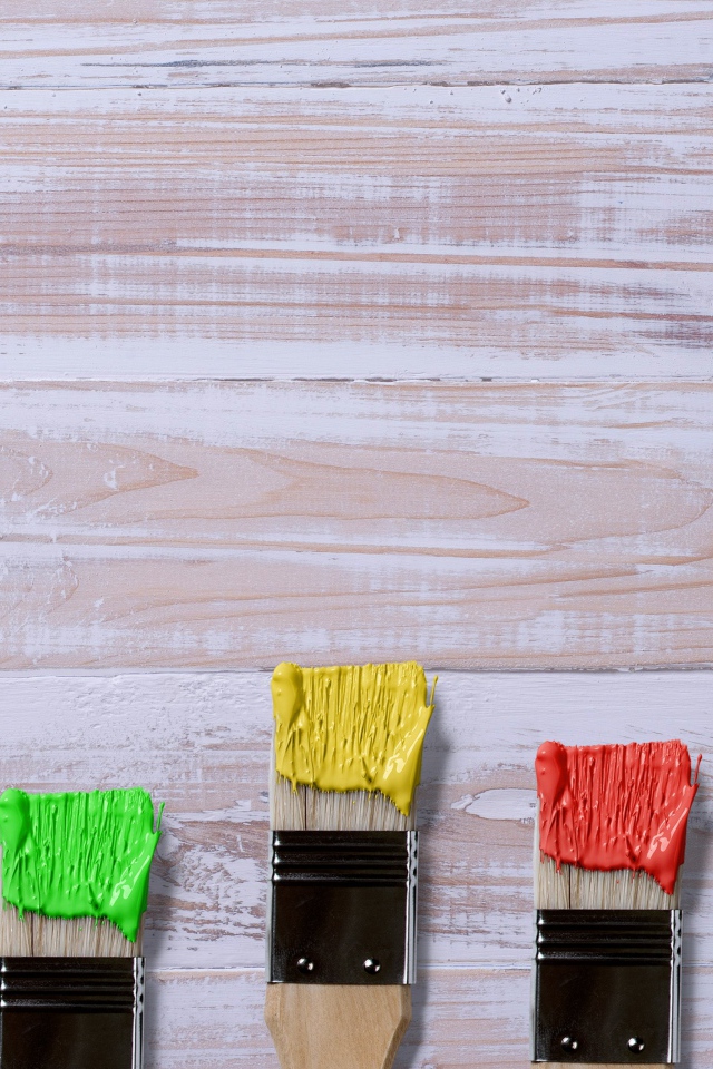 Кисточки в краске на деревянном фоне