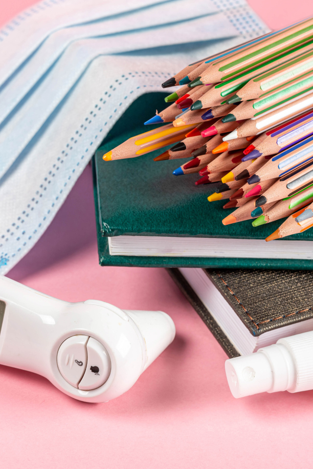 Карандаши, градусник, маска и блокнот на розовом фоне 