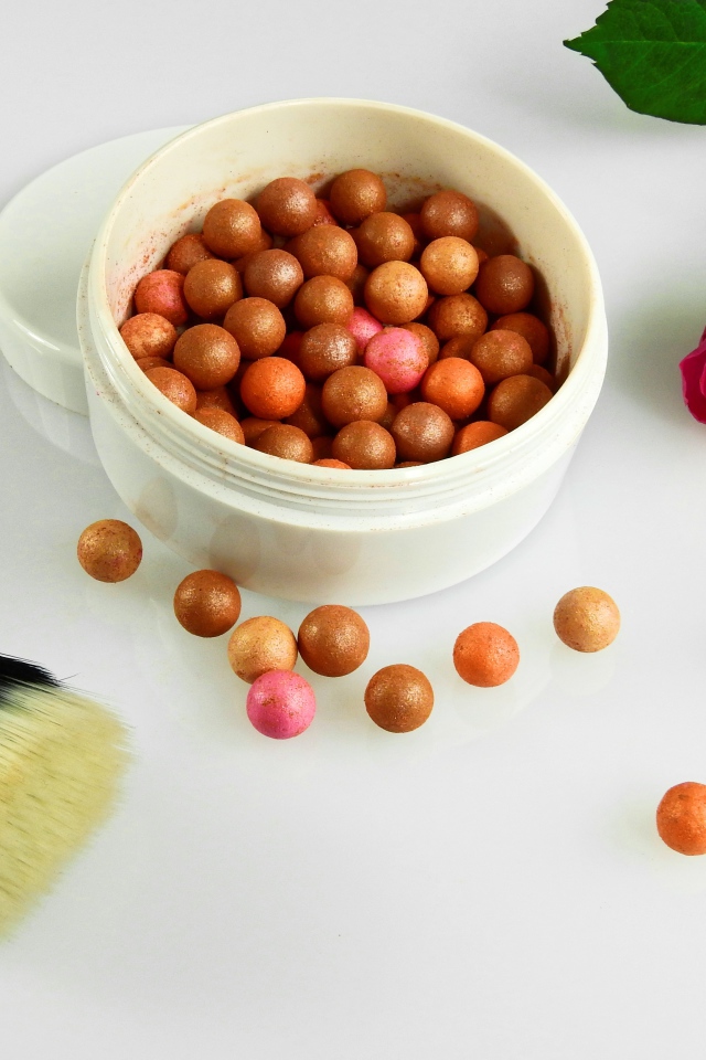 Шариковая пудра на белом фоне с кистью и розой