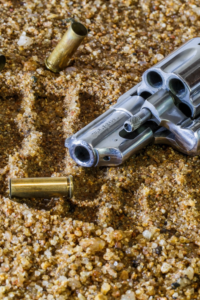 Револьвер с гильзами лежат на песке