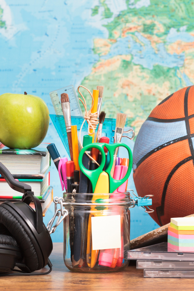 Школьные принадлежности на столе с наушниками и мячом 