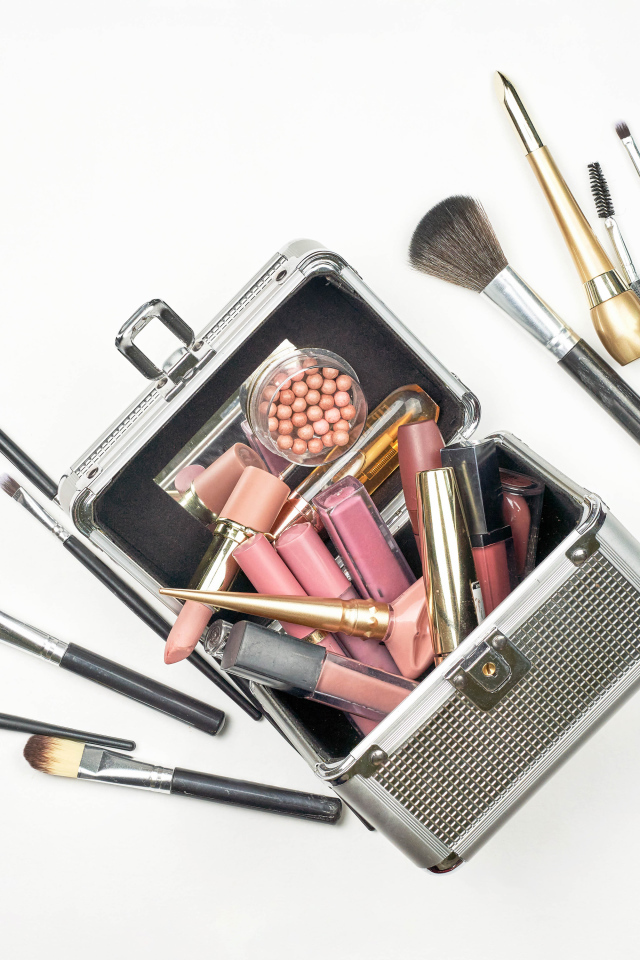 Набор косметики в чемодане на белом фоне