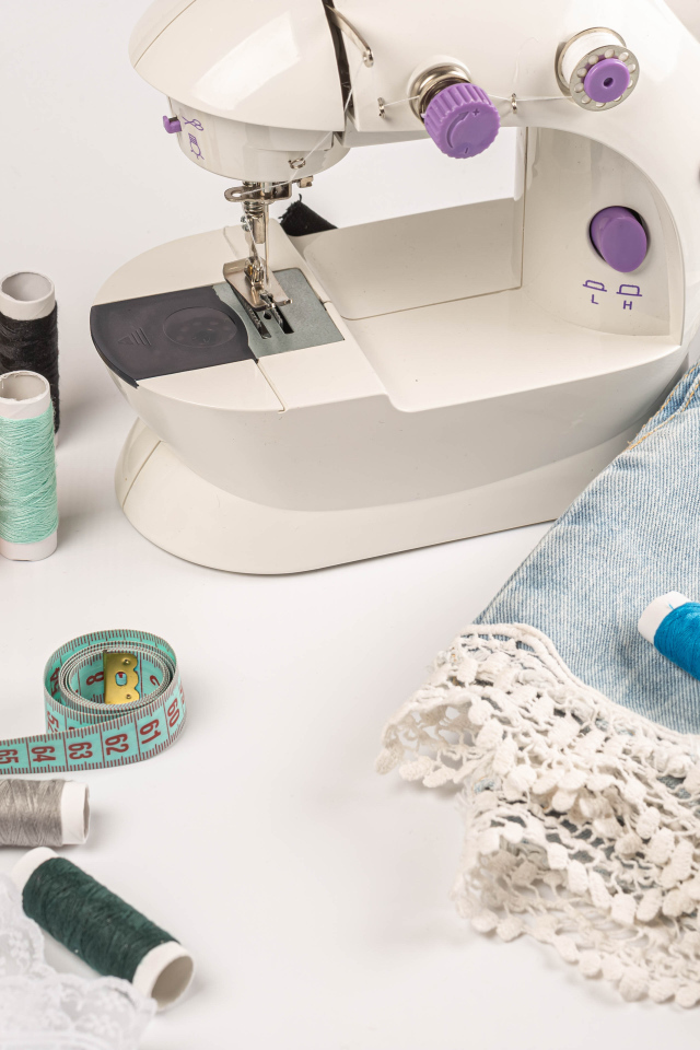 Швейная машинка,юбка и нитки на белом фоне 