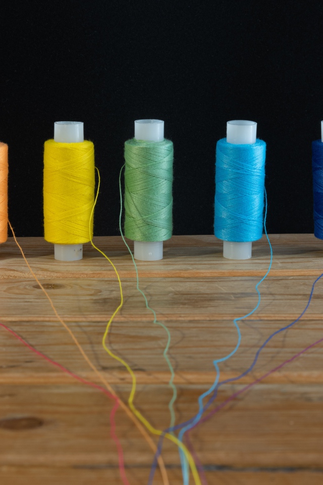 Катушки с разноцветными нитками на черном фоне 