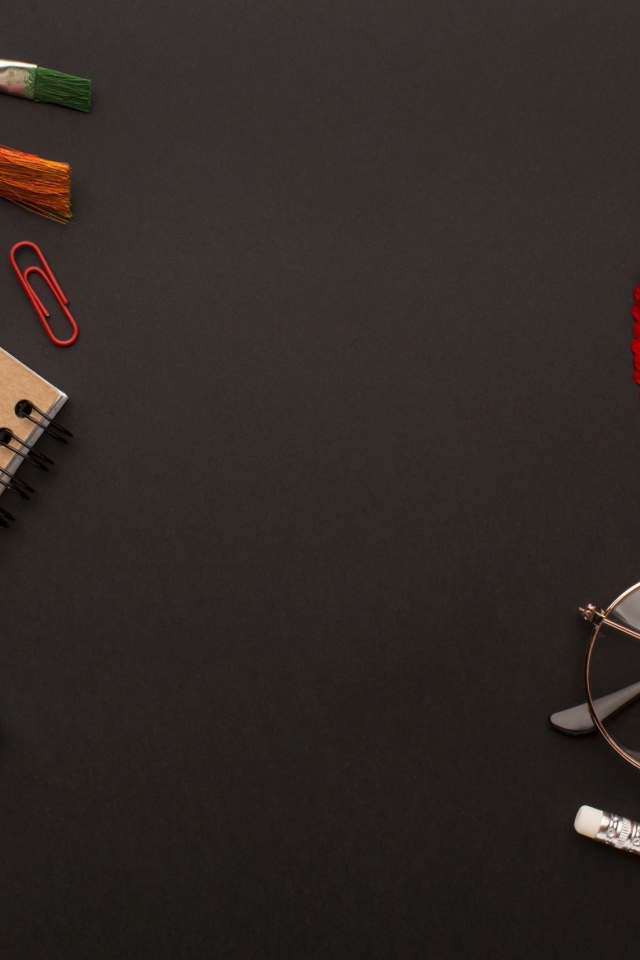 Канцелярские предметы, очки и герберы на черном фоне 