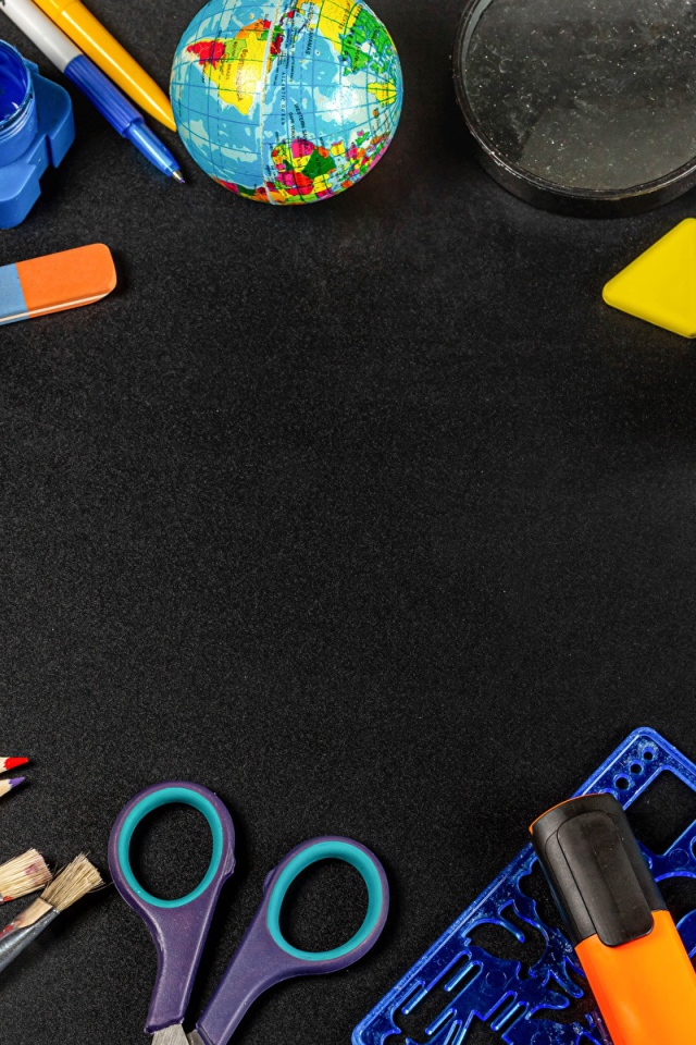 Канцелярские предметы, игрушки и маска на черном столе 