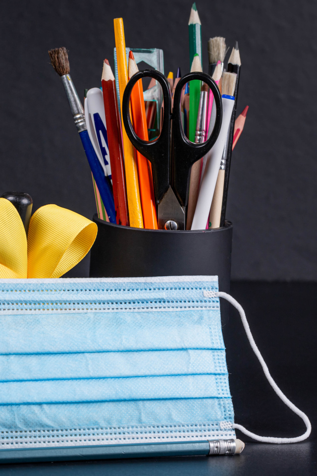 Канцелярские предметы на столе с медицинской маской