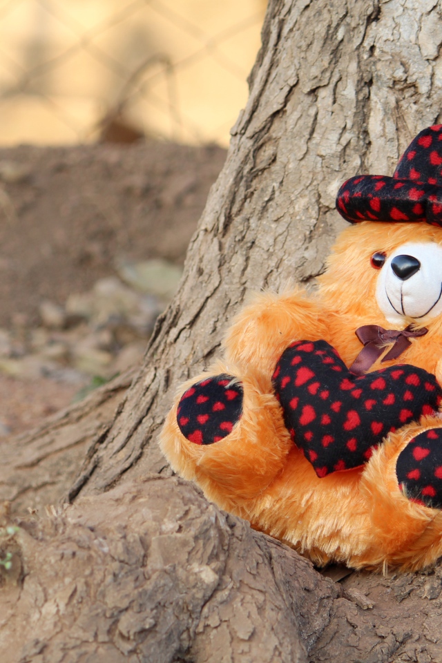 Медвежонок Тедди лежит под деревом