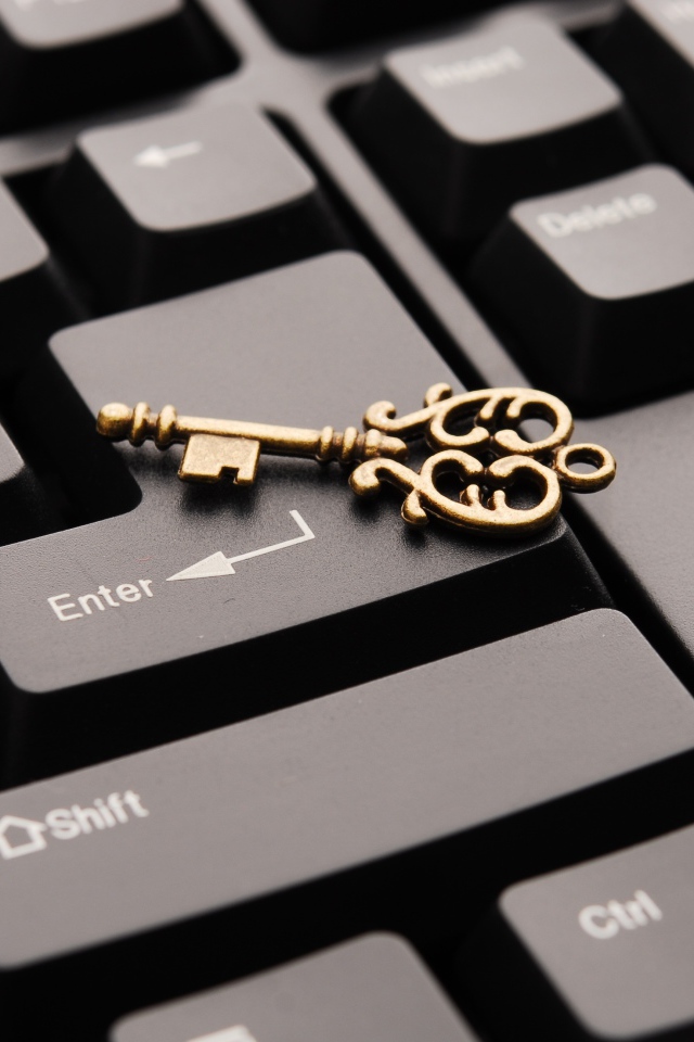 Золотой ключ лежит на черной клавиатуре