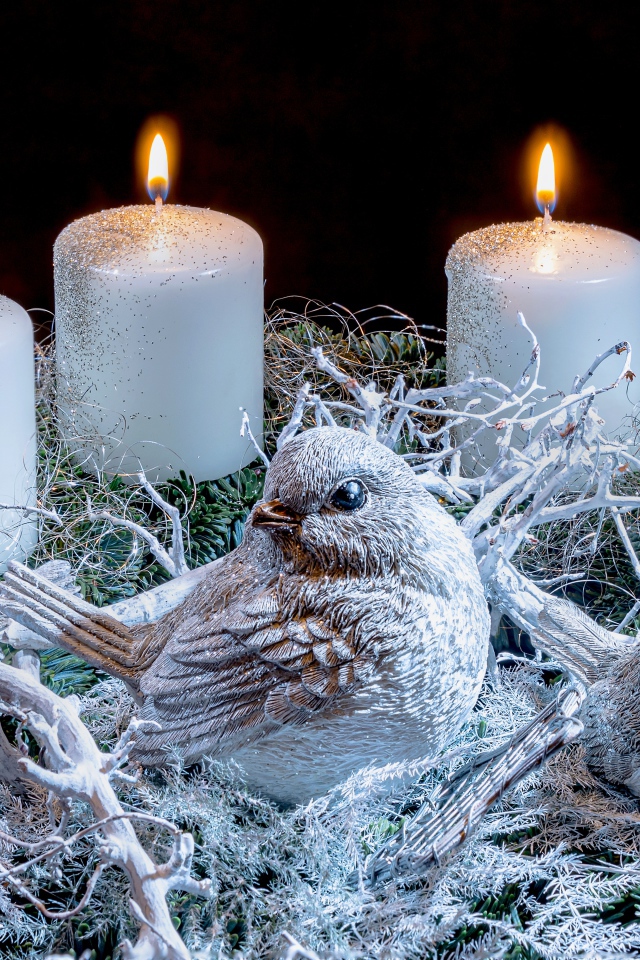 Три зажженные свечи со статуэтками птицами 