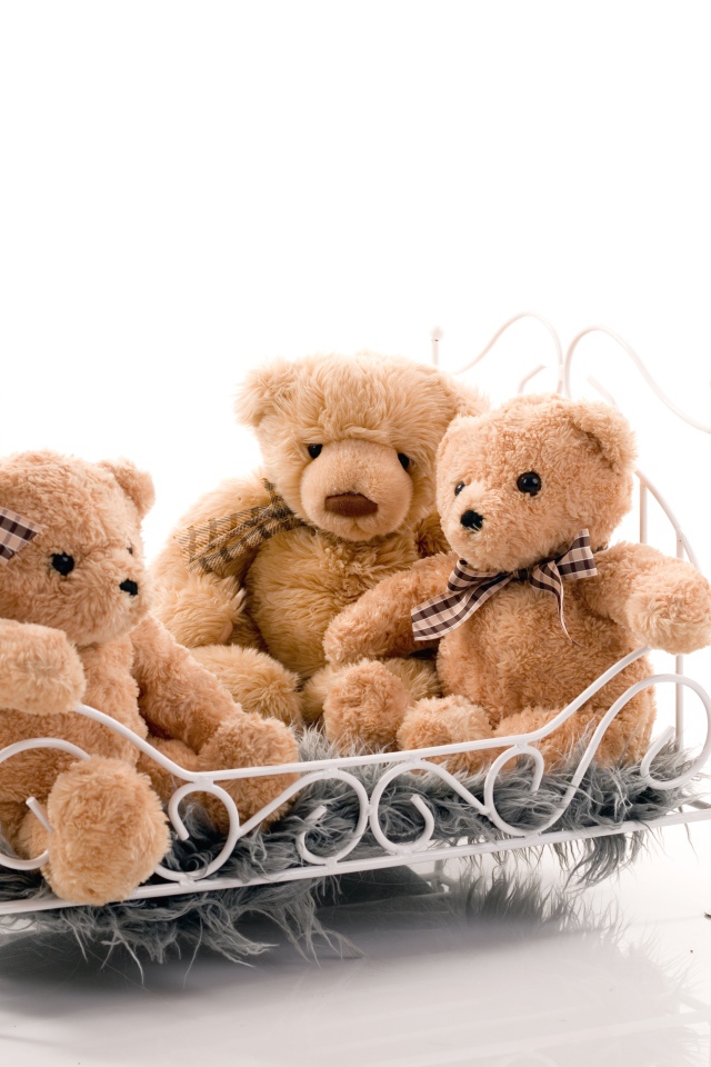 Три игрушечных медведя на кровати на белом фоне