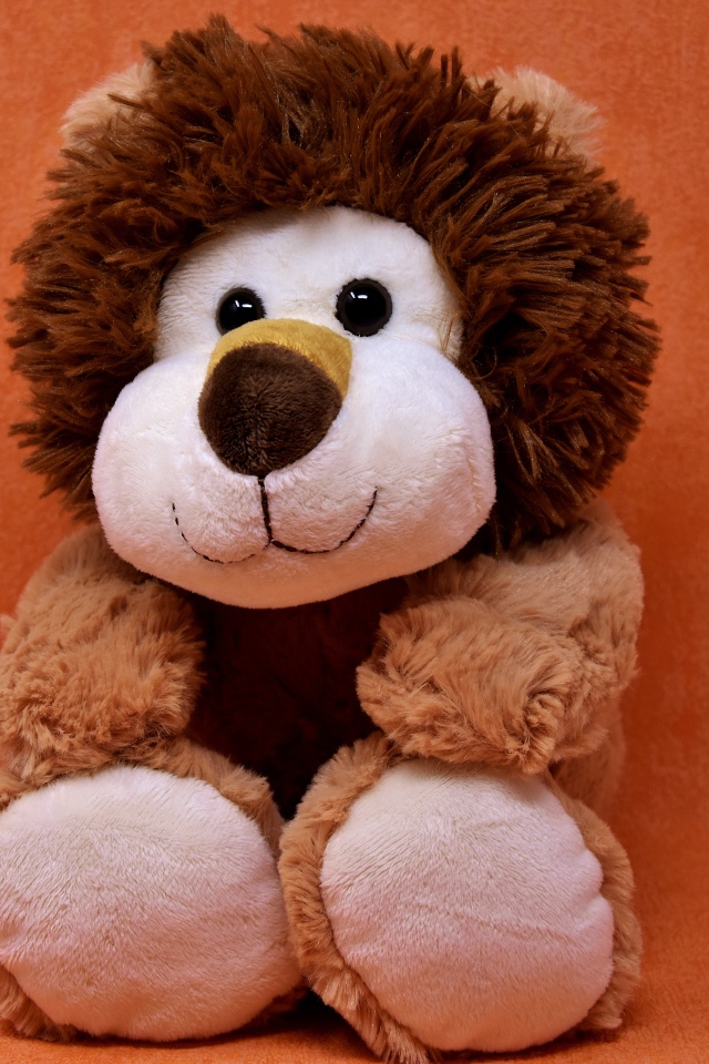 Игрушечный лев на фоне стены