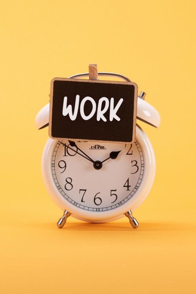 Белый будильник с табличкой на желтом фоне