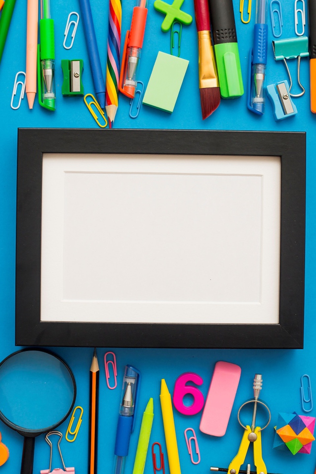 Белая рамка с разноцветными канцелярскими предметами на голубом фоне