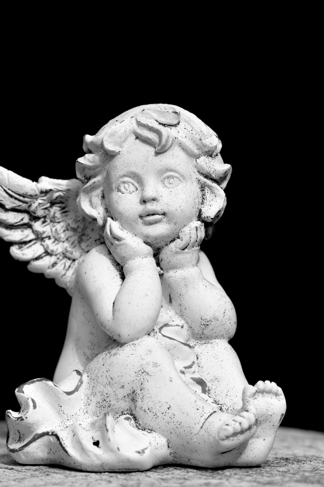 Белая статуэтка ангел на черном фоне