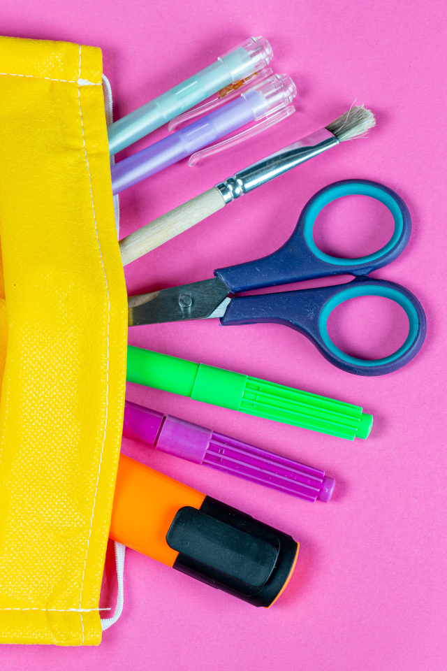 Желтая медицинская маска с ручками и ножницами на  розовом фоне