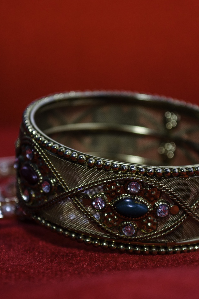 Красивый браслет с драгоценными камнями на красном фоне 