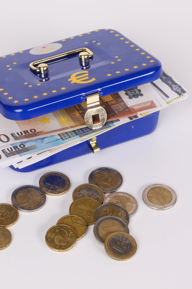 Синяя копилка чемодан с деньгами и монетами на сером фоне